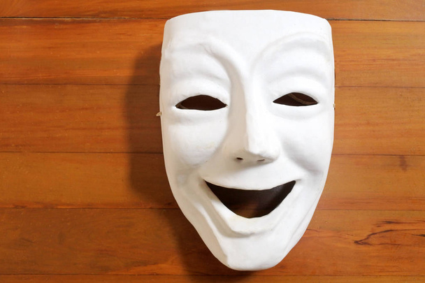 Белая маска счастливого человеческого лица с деревянным столом
 - Фото, изображение