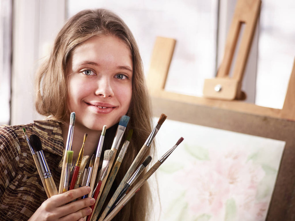 Pintura de artista sobre caballete en estudio. Pinturas de niña con pincel
. - Foto, imagen