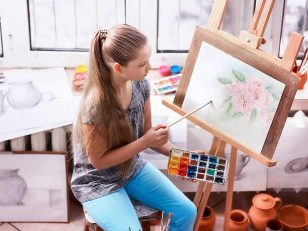 Artist painting on easel in studio. Girl paints with brush. - Photo, Image