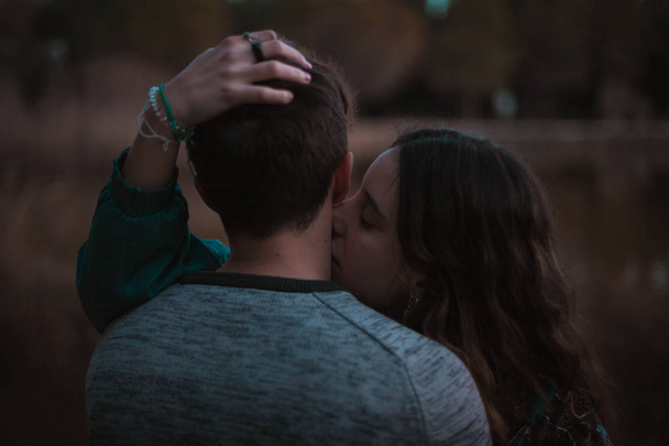 Egy aranyos spanyol pár birtoklás egy szép délután, átölelve és megcsókolta egymást egy parkban előtt egy tó, Sevilla, Spanyolország. - Fotó, kép