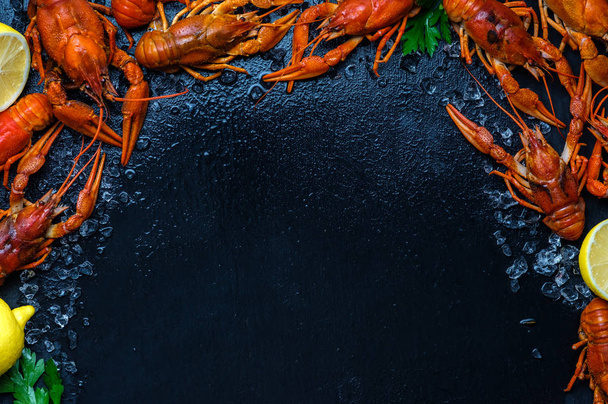 Fresh boiled crawfish with lemons and greens on a dark table wit - Photo, image