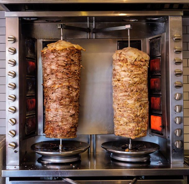 Two rotating skewered chicken and lamb meat grilled in stainless - Photo, Image
