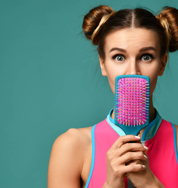 Jovem mulher surpreso fechar a boca com rosa e azul escova de pente de cabelo grande
  - Foto, Imagem