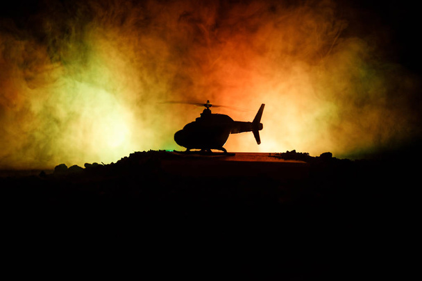 Askeri helikopter çatışma bölgesinden uçmaya hazır silüeti. Gece görüntüleri çöl sisli tonda sırt ile başlayarak helikopter ile dekore edilmiştir. Seçici odak. - Fotoğraf, Görsel