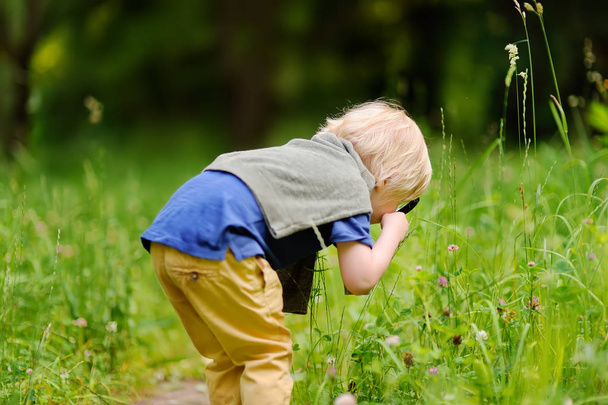 Charming kid exploring nature with magnifying glass - Foto, Bild