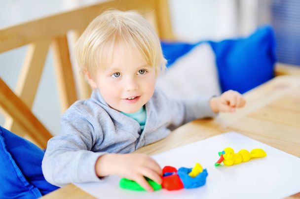 Chico creativo jugando con arcilla de modelado de colores en el jardín de infantes
 - Foto, imagen