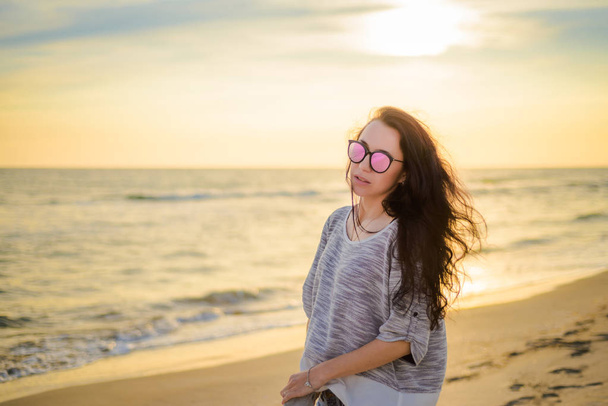 Μελαχρινή κοπέλα στο φόντο του ηλιοβασιλέματος της θάλασσας - Φωτογραφία, εικόνα