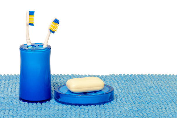 Blue glass with toothbrushes and soap dish with white soap. Isol - Photo, Image