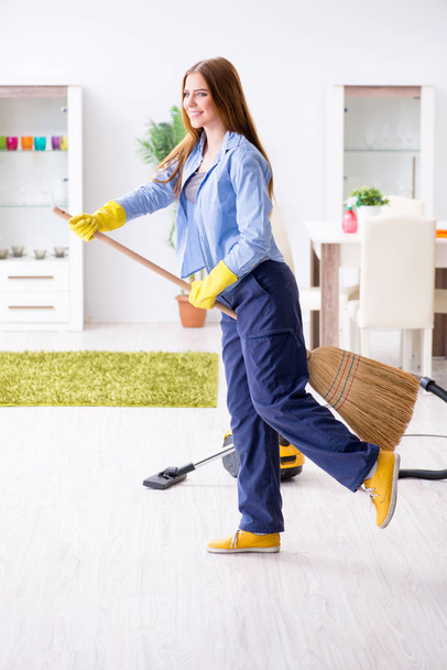 Νεαρή γυναίκα που καθαρίζει το πάτωμα στο σπίτι κάνοντας δουλειές - Φωτογραφία, εικόνα