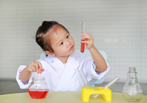 Asian child in scientist uniform holding test tube with liquid, Scientist chemistry and science education concept. - Foto, Bild