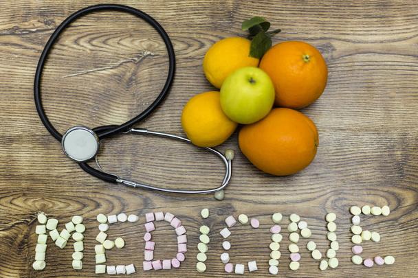 phonendoscope, citrons, oranges et médicaments formés de pommes avec guimauves sur panneau de bois
. - Photo, image