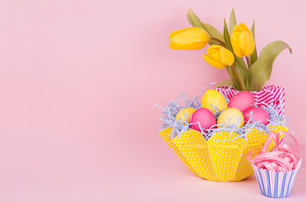 Gentle elegant soft pastel easter decoration - painted eggs, yellow tulips, cupcake on pink background, copy space. - Foto, Imagen