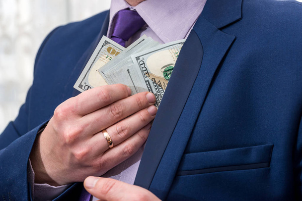 zakenman ons geld steken in zijn zak pak - Foto, afbeelding