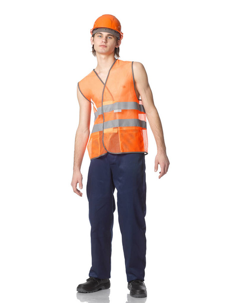 Genç bir işçi bir yaz turuncu örgü yelek bir kask içinde. - Fotoğraf, Görsel