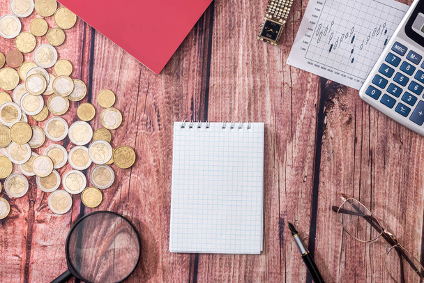 notepad, euro coin, calculator with glasses on desk. - Фото, зображення