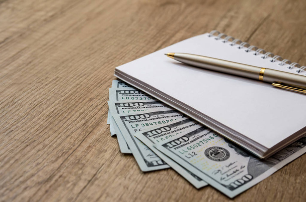 американська сотня доларів і ручка і порожня нота на столі
 - Фото, зображення
