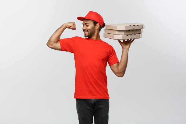 Doručení koncepce - portrét Strong African American doručovatel ukazuje své svaly s pizza box balíčky. Izolované na šedé studio pozadí. Kopírovat prostor. - Fotografie, Obrázek
