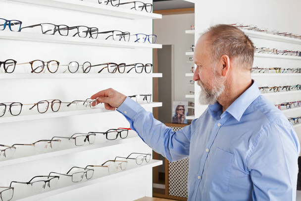 Elderly man in optics store - Фото, изображение