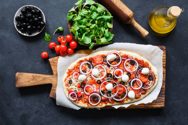 Homemade pizza preparation. Pizza ingredients on dark background - Fotó, kép