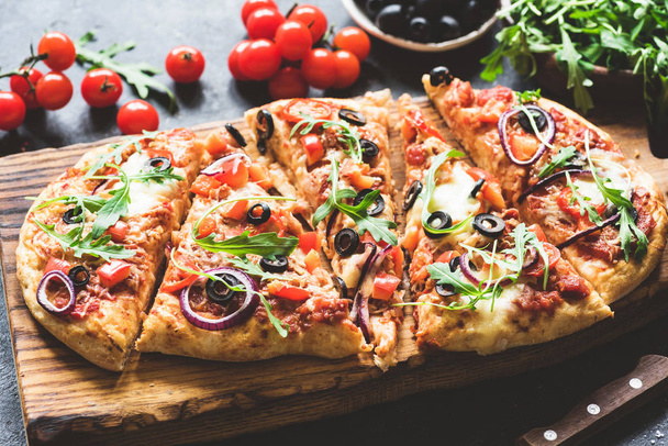 Homemade flatbread pizza sliced on wooden cutting board - Фото, изображение
