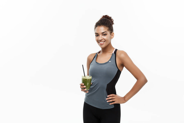 Pořádku a Fitness koncept - krásná africká americká dívka ve sportu oblečení hospodářství plastovou láhev s vodou po cvičení. Izolované na bílém studio pozadí - Fotografie, Obrázek