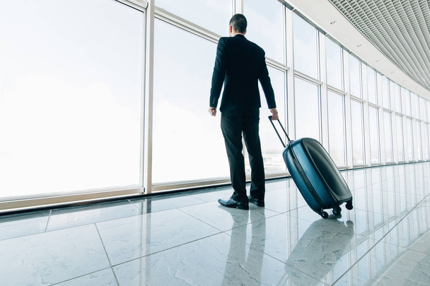 Business man at international airport moving to terminal gate for airplane travel trip. Mobility concept and aerospace industry flight connections. - Φωτογραφία, εικόνα