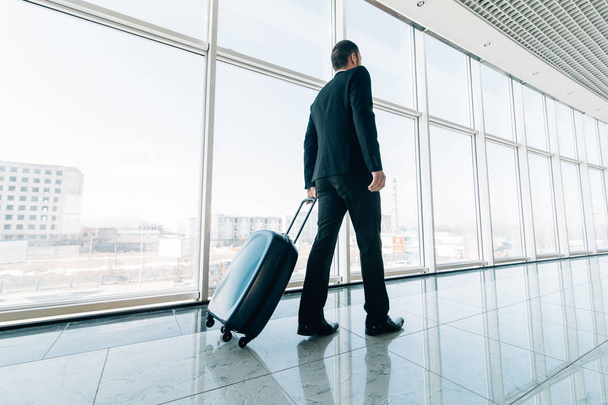 Человек в аэропорту с чемоданом идет к воротам. Бизнес поездка
. - Фото, изображение