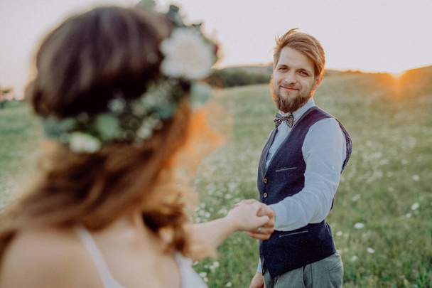 Beautiful bride and groom at sunset in green nature. - Zdjęcie, obraz