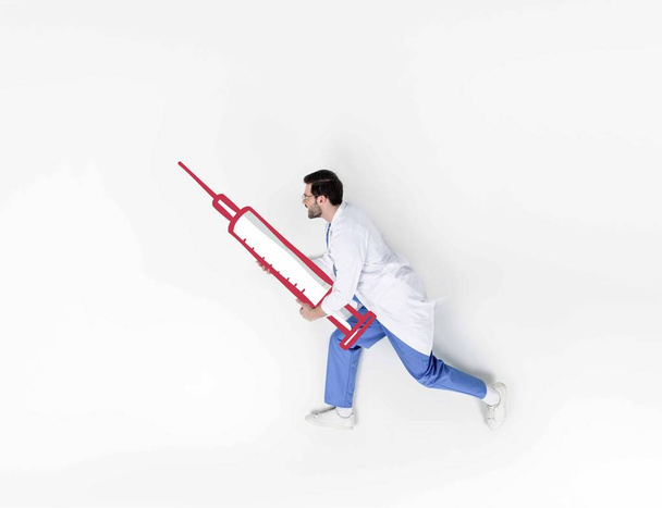 colagem criativa de bonito jovem médico correndo e segurando seringa desenhada
 - Foto, Imagem