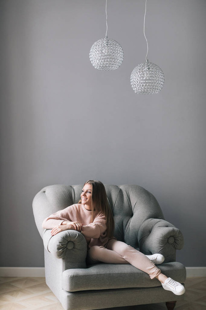 Young woman at home sitting on chair relaxing. - Foto, afbeelding