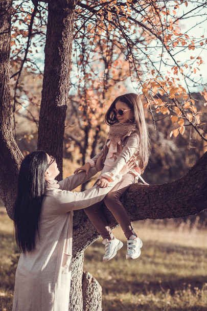 Beautiful young woman and her kid in autumn garden - Foto, afbeelding