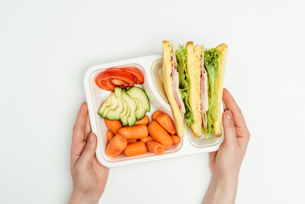 cropped image of woman holding lunch box with sandwiches isolated on white - Photo, Image