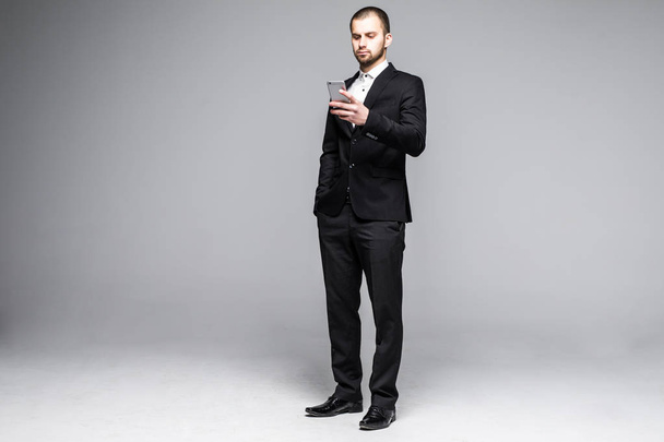Young business man typing message on smartphone touch screen. Full body length portrait isolated over white studio background. - Fotoğraf, Görsel