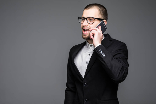 Happy businessman talking on the mobile phone over gray background. - 写真・画像