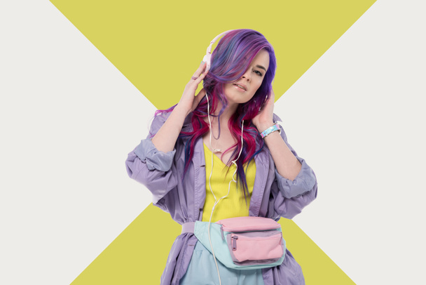 fashionable young woman with colorful hair in purple trench coat listening music with headphones - Foto, afbeelding