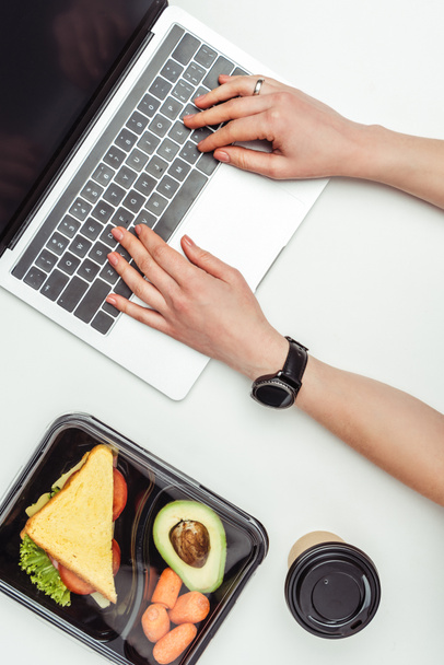 女性白で隔離お弁当の食品とのテーブルでノート パソコンを使用してのトリミングされた画像 - 写真・画像