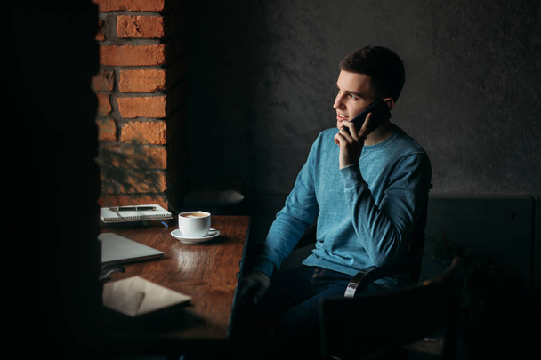Człowiek z telefonu w kawiarni siedzi naprzeciwko okna - Zdjęcie, obraz