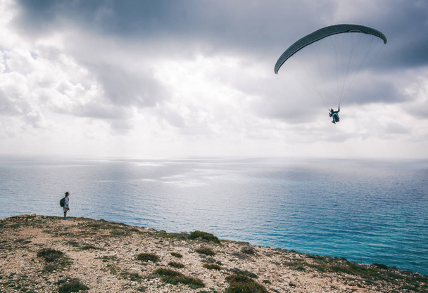 The paraglider flies over the sea, the girl watches him from the - Foto, immagini