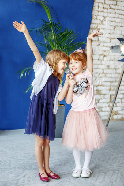 Két kis mosolygó gyerekek táncolni és énekelni a karaoke. A co - Fotó, kép