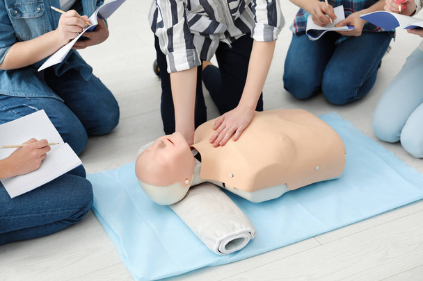 Group of people practicing CPR on mannequin at first aid class - Valokuva, kuva