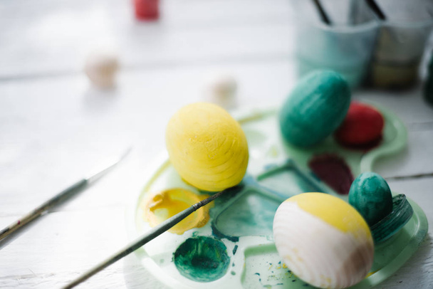 The process of painting Easter eggs still life on a white wooden background - Fotoğraf, Görsel