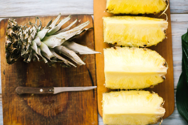 Sliced fresh pineapple on a wooden background in sunlight - Fotó, kép