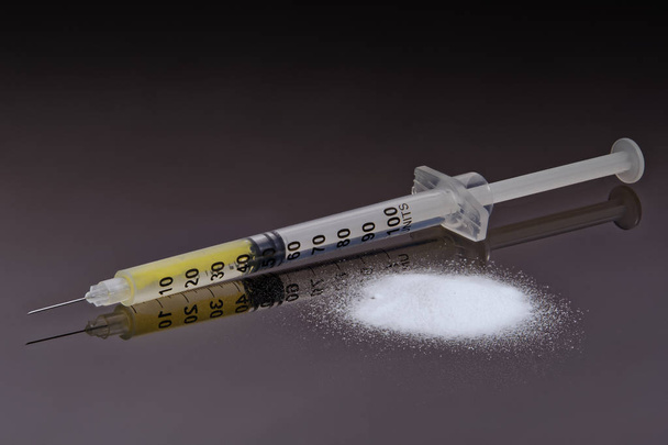 Hard drug in syringe and heroin on a texture background - Photo, Image