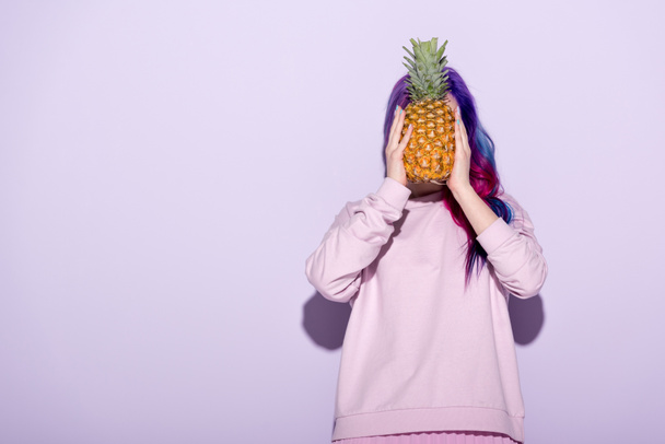 beautiful young woman with colorful hair and pink sweatshirt holding pineapple - Photo, Image