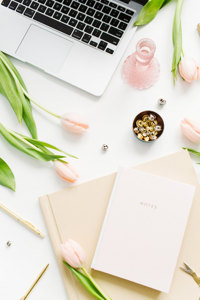 Γυναίκα γραφείο σπίτι με το laptop, λουλούδια ροζ τουλίπα, σημειωματάριο, αξεσουάρ και καλλυντικών σε λευκό φόντο. Flatlay, το top view μόδα blog σύνθεση. - Φωτογραφία, εικόνα