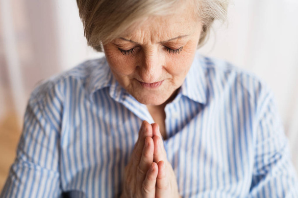 A senior woman praying at home. - Foto, imagen