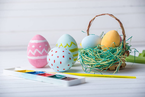 Huevos de Pascua coloridos con pinturas pintadas a mano sobre un fondo de madera blanca. Tarjeta de primavera festiva
 - Foto, imagen