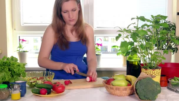 Těhotná žena řezání ředkvičky zelenina na prkénku - Záběry, video