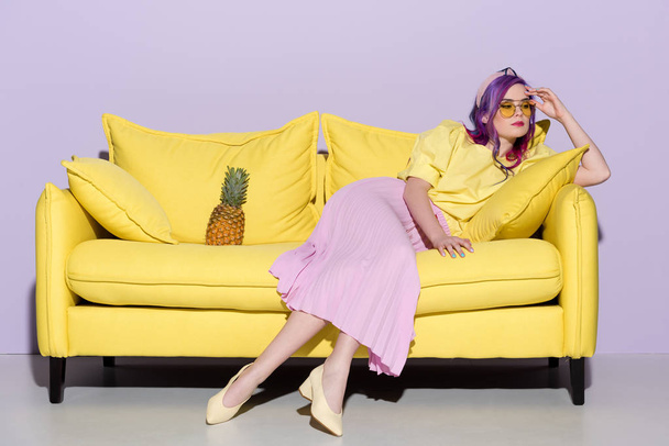 stylish thoughtful woman sitting on yellow couch with pineapple - Foto, Bild