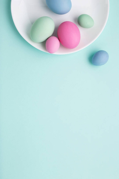 Conceptual Easter vertical background with white plate and paint - Фото, изображение